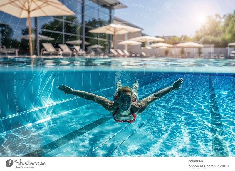 Ober- und Unterwasserfoto einer Frau, die im Schwimmbad eines Hotels oder Kurortes schwimmt Sonnenschirm Liege oben Hälfte Split thermisch Resort platschen