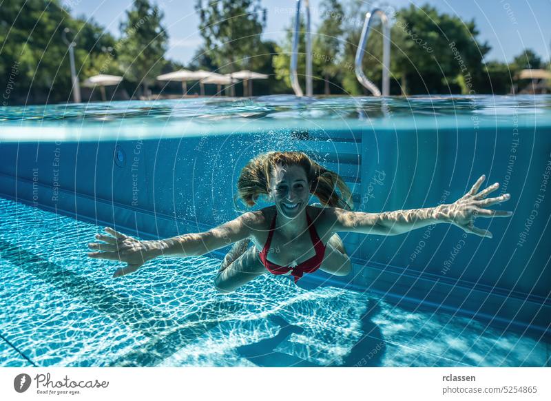 Split oben und unter Wasser Foto einer Frau schwimmen im Pool während des Sommerurlaubs in einem Hotel Laufmasche Handläufe Hälfte thermisch Resort platschen