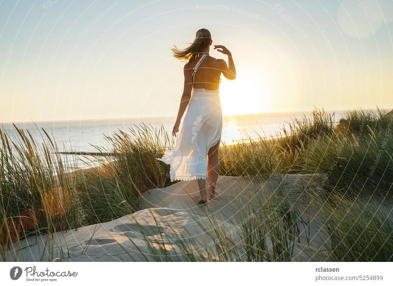schöne Frau geht barfuß durch Sanddünen zum Meer bei Sonnenuntergang energetisch Hippie Boho Abenteuer allein Schönheit wüst Kleid Düne Mode frei Freiheit