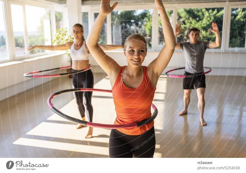 Junge Frauen und Männer machen Hula-Hoop-Reifen während einer Übung Klasse in einem Fitnessstudio. Gesunder Sport Lebensstil, Fitness, Gesundes Konzept. Club