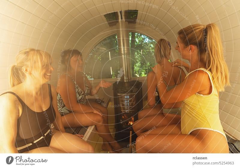 Gruppe von Mädchen sitzen im Badeanzug in einer heißen Holzfass-Sauna in Norwegen. Sie sind entspannt und genießen den Urlaub, während sie in der finnischen Saunakabine entspannen.