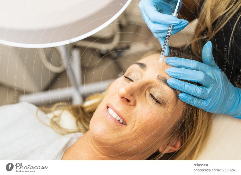 Nahaufnahme einer Anti-Aging-Gesichtsinjektion in die Augenbraue oder Stirn einer Patientin Lupe Ästhetik Anti-Falten Vorschein Kosmetikerin Schönheitsklinik