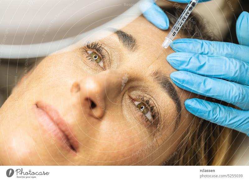 Plastische Chirurgie. Junge Frau, die in einer Schönheitsklinik eine Anti-Aging-Gesichtsinjektion in die Stirn erhält Lupe Ästhetik Anti-Falten Vorschein