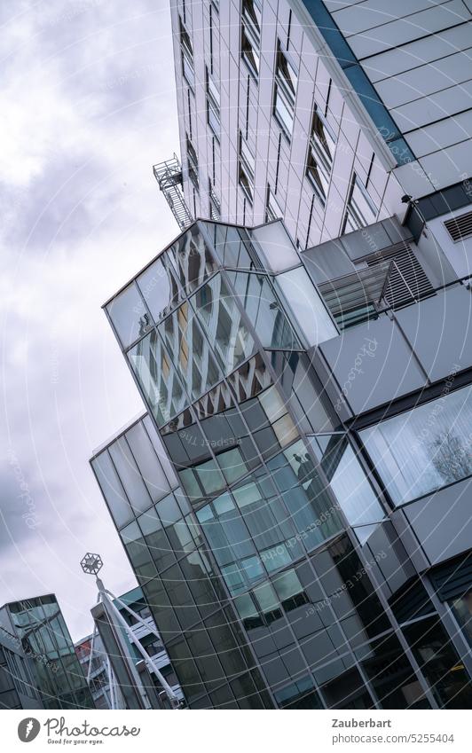 Moderne Glasfassade in der Stadt, gekippt vor dramatischem Himmel Fassade kippen grau stadt städtisch urban kalt kühl unwohnlich ungemütlich gleichgewicht