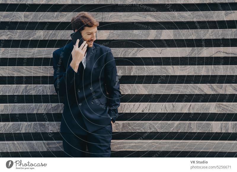 Geschäftsmann in eleganter schwarzer Kleidung telefoniert mit Partner konzentriert unten hält Smartphone Business Mann Internet Technik & Technologie Telefon