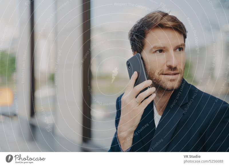 Nachdenklicher männlicher Unternehmer, der in die Ferne blickt, nimmt einen Anruf mit dem Mobiltelefon entgegen Business Mann Technik & Technologie