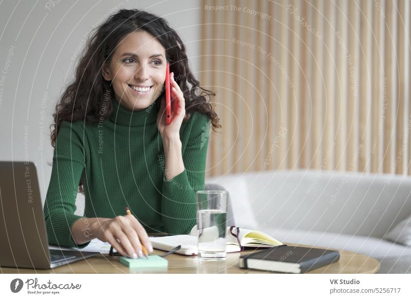 Lächelnde Geschäftsfrau, die mit dem Handy kommuniziert und Bestellungen entgegennimmt und Informationen auf einen Zettel schreibt reden Telefon Arbeit