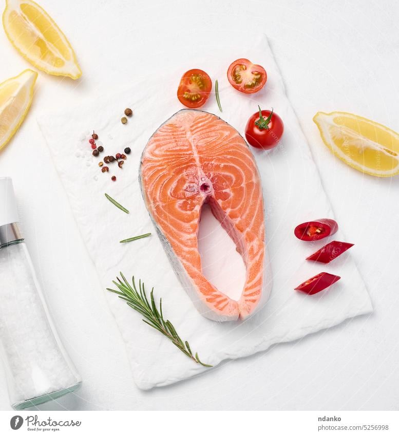 Rohes Stück Lachs, Zitronenscheiben und Gewürze auf einer weißen Tafel, Ansicht von oben roh Fisch Lebensmittel Spielfigur frisch Hintergrund Meeresfrüchte