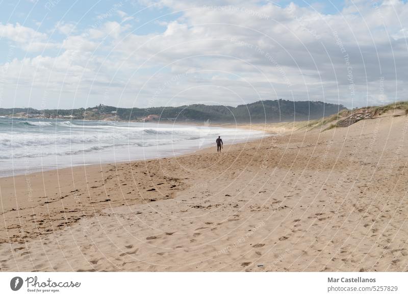 Mann bei einem Strandspaziergang am Strand von Lanzada, Galicien, Spanien Ufer MEER Küstenlinie Meereslandschaft Brandung Sand Landschaft sumer reisen winken