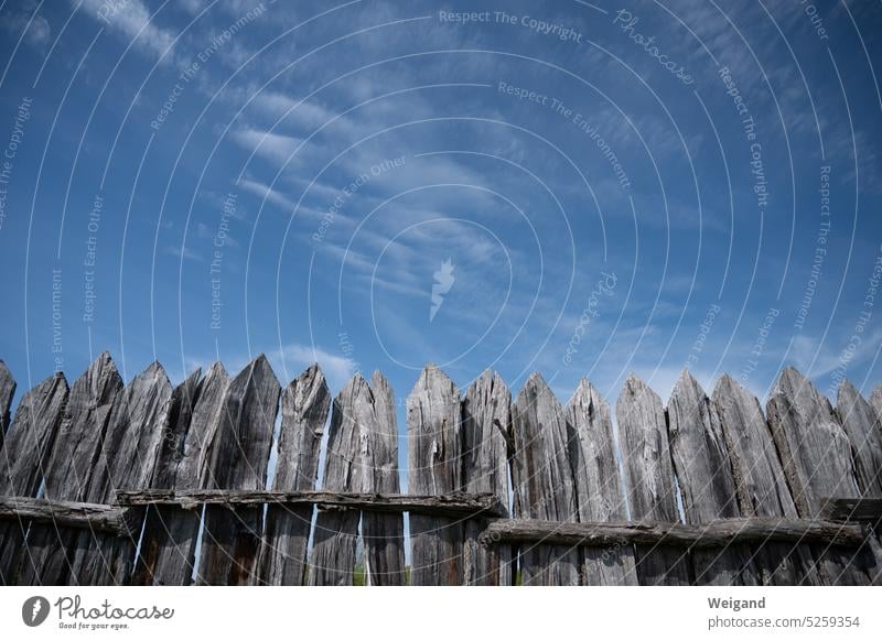 Perspektive gen leuchtend blauen Himmel mit altem Lattenzaun aus Holz mit spitzen Zaunenden im Vordergrund Holzlatten Grenze Natur blauer Himmel Wegweiser