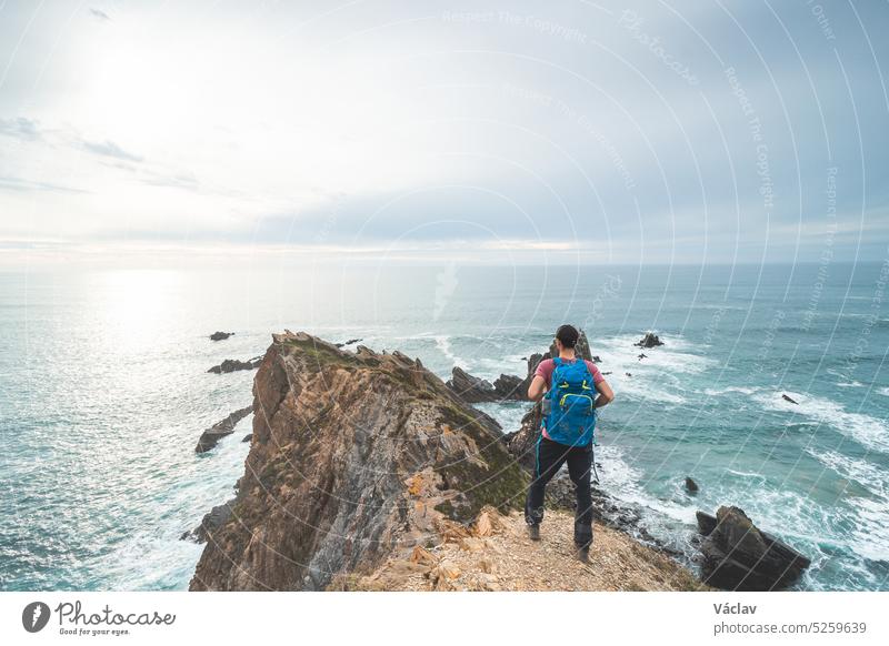 Rucksacktourist rastet auf seiner Reise entlang der Atlantikküste im Westen Portugals, entlang des berühmten Fisherman Trail. Ausruhen bei Sonnenuntergang