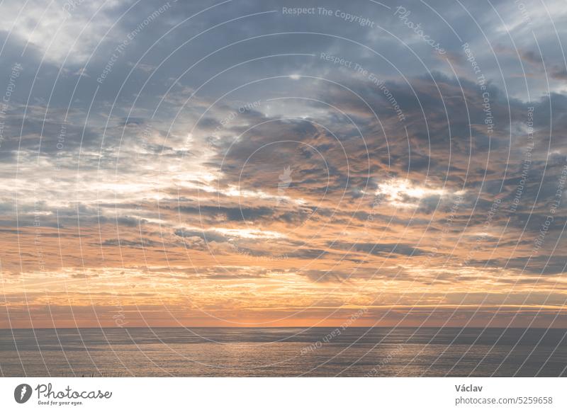 Die letzten Sonnenstrahlen beleuchten die über den Himmel fliegenden Wolken, und die Reflexion des Meeres beleuchtet die umliegenden Klippen. Harmonie der Farben. Traumlandschaft. Sonnenuntergang in der Algarve-Region, Portugal