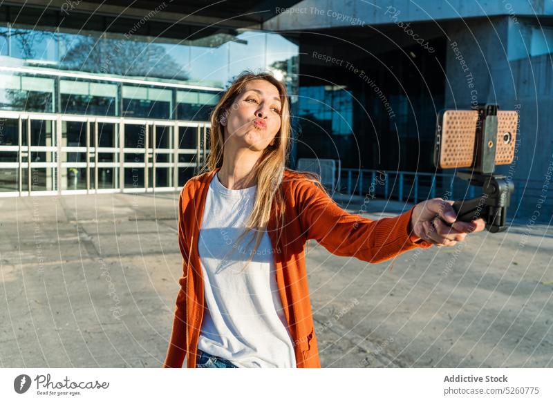 Junge Frau sendet Kuss bei der Aufnahme von Selfie auf der Straße schmollende Lippen Smartphone Großstadt Lächeln Stil fotografieren urban jung brünett Glück