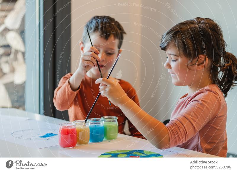 Kinder gestalten gemeinsam Umweltplakate Farbe Waschen Pinselblume kreativ Plakat Wasser Geschwisterkind Glück Tisch Tasse Zusammensein Kindheit Freund Junge