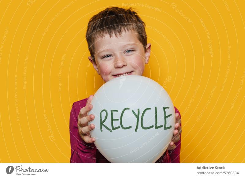 Fröhlicher Junge mit Recycling-Ballon Luftballon wiederverwerten Glück zeigen Lächeln Umwelt Ökologie farbenfroh hell lässig Kind Aufschrift positiv heiter