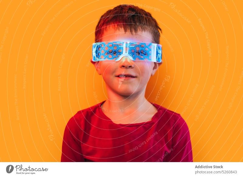 Junge mit leuchtender, futuristischer Schutzbrille Brille neonfarbig glühen Ornament Porträt farbenfroh hell Lächeln Stil Kind lebhaft T-Shirt glänzend