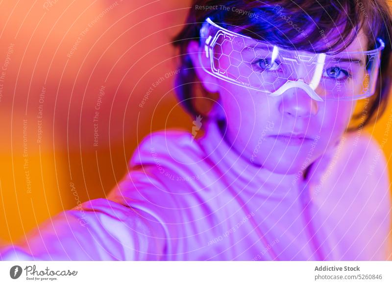 Mädchen mit leuchtender futuristischer Brille neonfarbig Ornament Cyberpunk Porträt Farbe hell Kind dunkles Haar Schutzbrille Individualität glühen Jacke