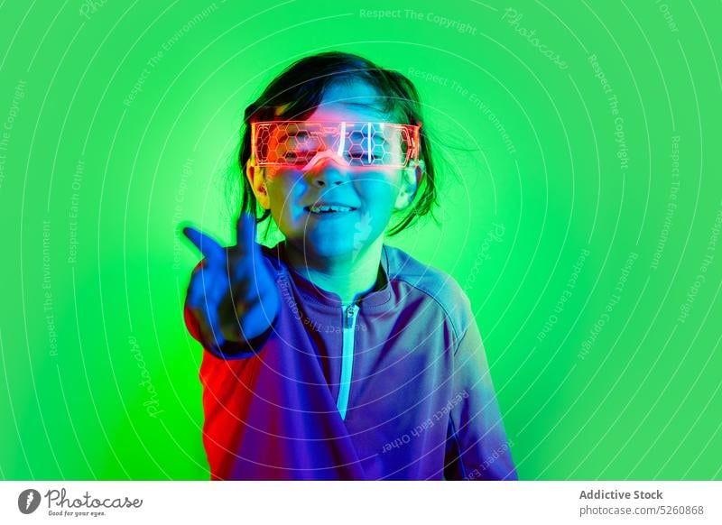 Lustiges Mädchen mit intelligenter Brille berührt unsichtbares Objekt Kind berühren Air klug VR Schutzbrille spielen Spiel futuristisch lustig