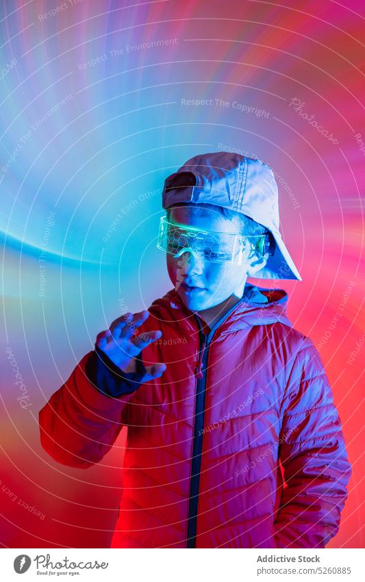 Futuristischer Junge, der mit einer digitalen Schnittstelle interagiert interagieren futuristisch Cyberspace Kontrolle Presse neonfarbig leuchten hell Stil