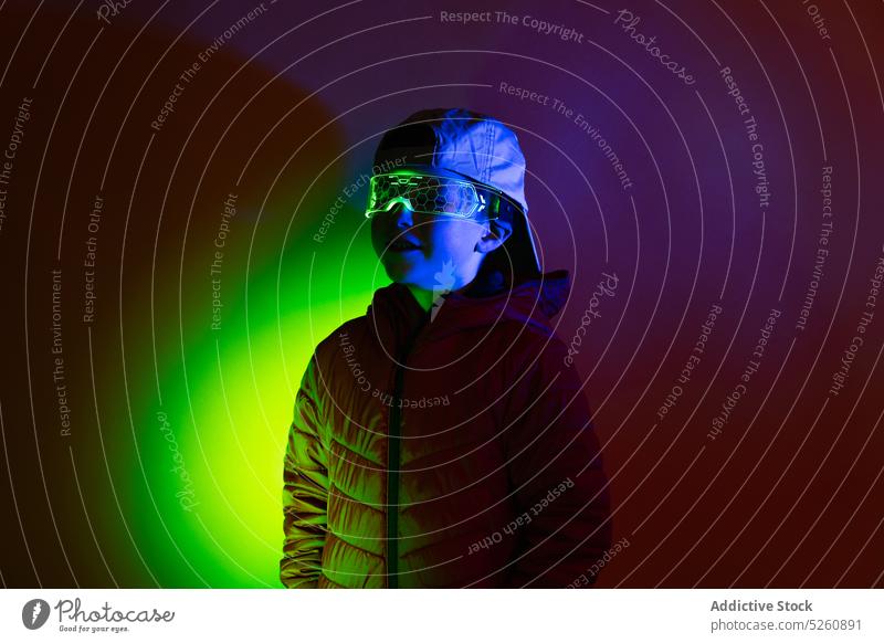 Kind mit futuristischer Brille unter Neonbeleuchtung Oberbekleidung dunkel leuchten neonfarbig Lächeln Schutzbrille Glück Stil Inhalt glühen Verschlussdeckel