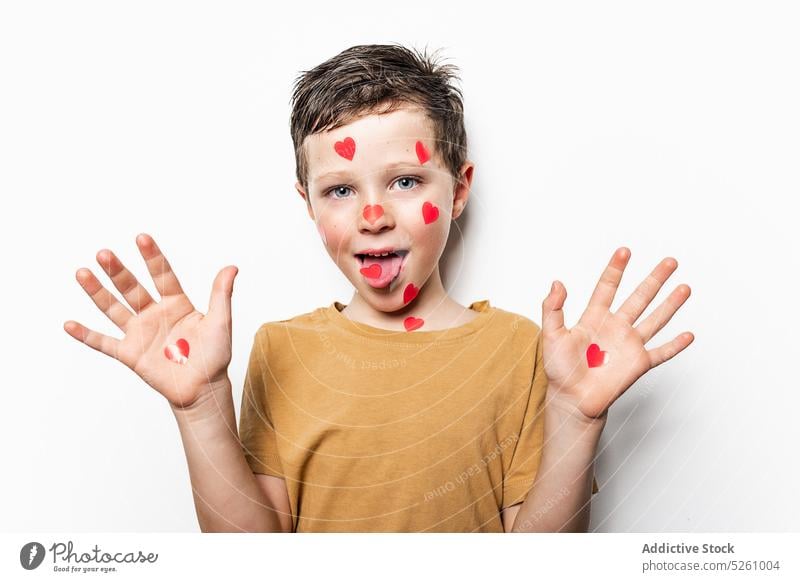 Junge mit Papierherzen, die Hände und Zunge zeigen Hand Herz niedlich Liebe Grimasse lustig Symbol ausspannen Kindheit spielerisch bezaubernd heiter Handfläche