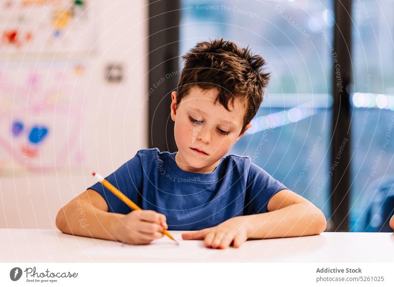 Junge sitzt am Tisch und zeichnet zeichnen heimwärts Fenster kreativ Hobby Abend Kind froh Kindheit Bleistift Skizze niedlich Vorstellungskraft lässig