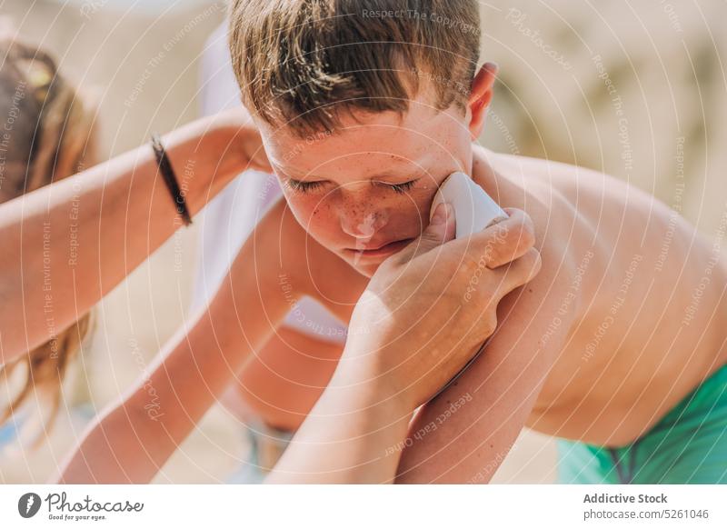 Crop-Frau trägt Sonnenschutzmittel auf das Gesicht eines Jungen auf bewerben Kind behüten Pflege MEER Ufer Natur Lanzarote Papageienstrand Spanien Europa