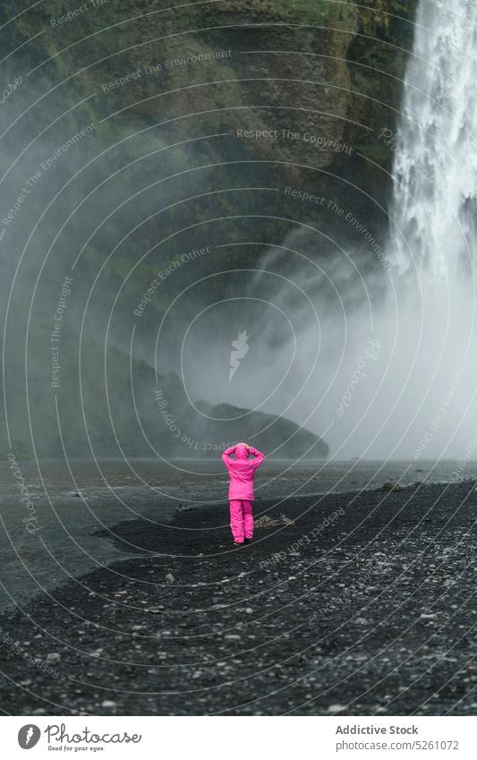 Unbekannter Reisender in der Nähe eines Wasserfalls Frau felsig Küste Fluss Natur bewundern Landschaft Island Europa erkunden Abenteuer Tourismus frisch