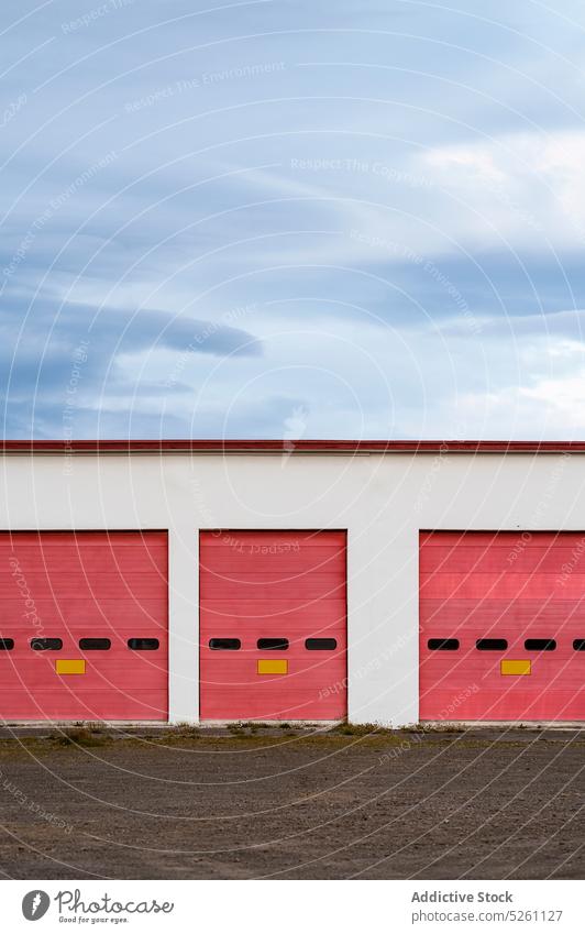 Garage mit roten Toren unter bewölktem Himmel Landschaft Lager Außenseite modern Gebäude Fassade Gate sehr wenige Eingang Island Europa industriell wolkig