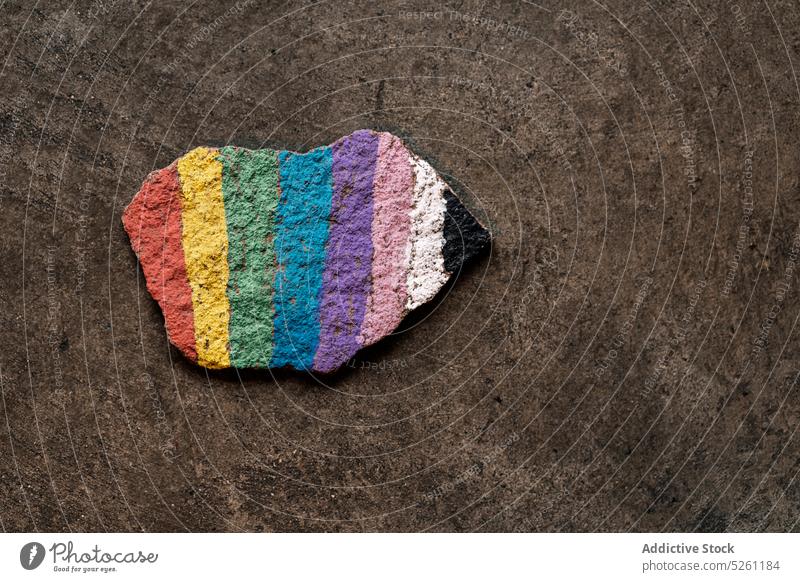 Regenbogenfarbiges Stück Stein auf grauem Hintergrund lgbt Farbe Fahne Symbol Stolz farbenfroh gleich Konzept schwul Toleranz Homosexualität lesbisch Kunst