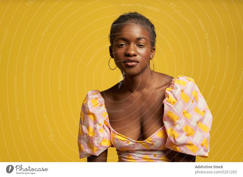 Schwarze Frau in rosa Outfit in der Nähe der gelben Wand Stil farbenfroh Model ernst jung lässig selbstbewusst ethnisch Afroamerikaner schwarze Frau Vorschein
