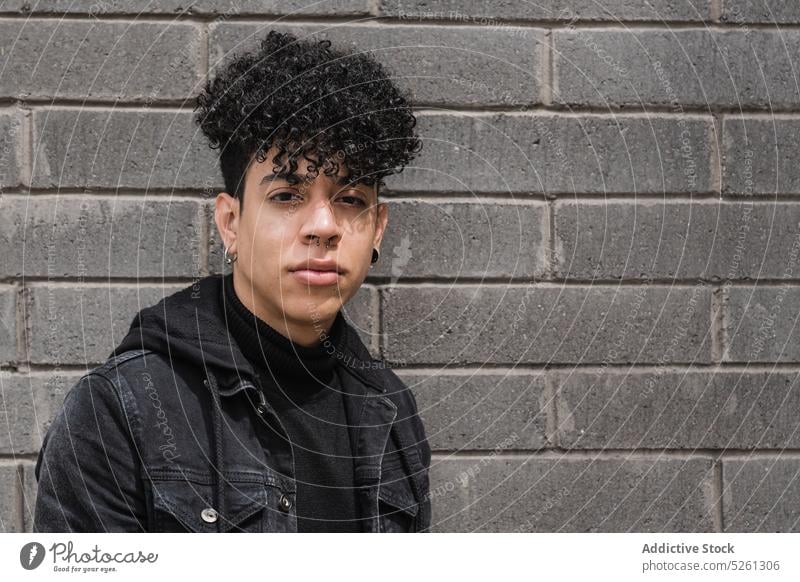 Positiv eingestellter hispanischer Migrant schaut in die Kamera Mann Porträt Schüler Backsteinwand einwandern Lifestyle Straße positiv selbstbewusst Typ lässig