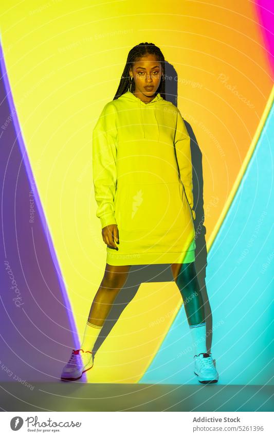 Junge schwarze Frau steht im Studio gegen gelbe und blaue Lichter Model Geometrie neonfarbig Einfluss leuchtend glühen Linie Studioaufnahme Afroamerikaner