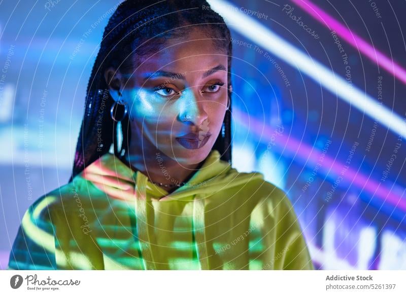 Schwarze Frau steht in einem Studio mit Neonröhren Model Porträt mehrfarbig neonfarbig Licht Einfluss Projektor selbstbewusst Studioaufnahme Afroamerikaner