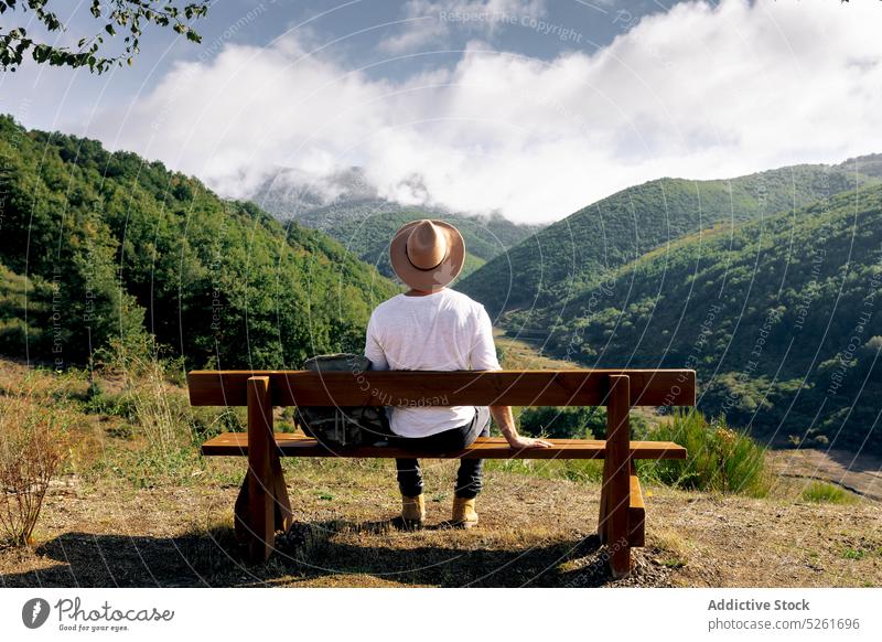 Männlicher Tourist ruht sich auf einer Bank in den Bergen aus Mann Reisender Rucksack ruhen bewundern Berge u. Gebirge Ausflugsziel Landschaft Tourismus jung