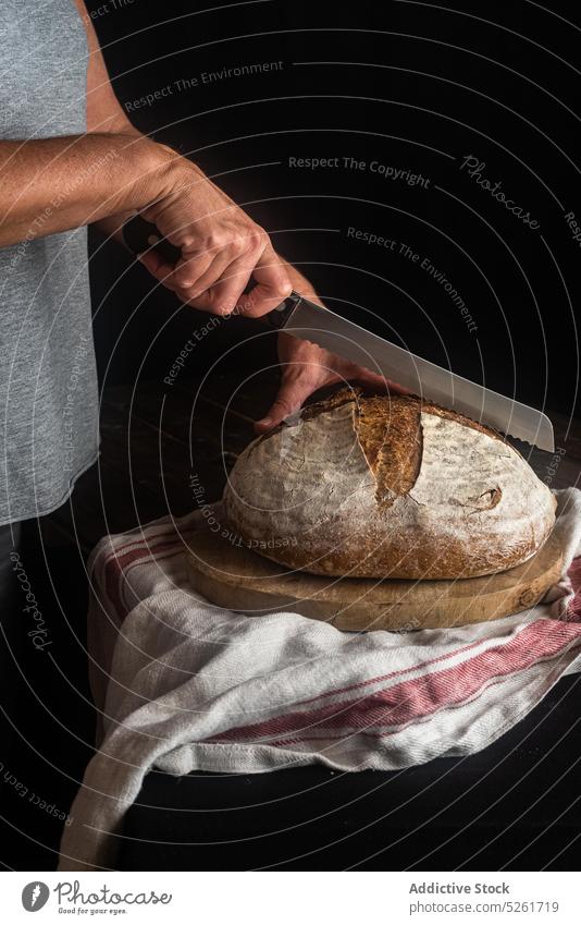 Person, die Brot mit einem Messer schneidet geschnitten Brotlaib Kunstgewerbler Sauerteig gebacken Roggen ganz Schneidebrett Bäcker organisch natürlich