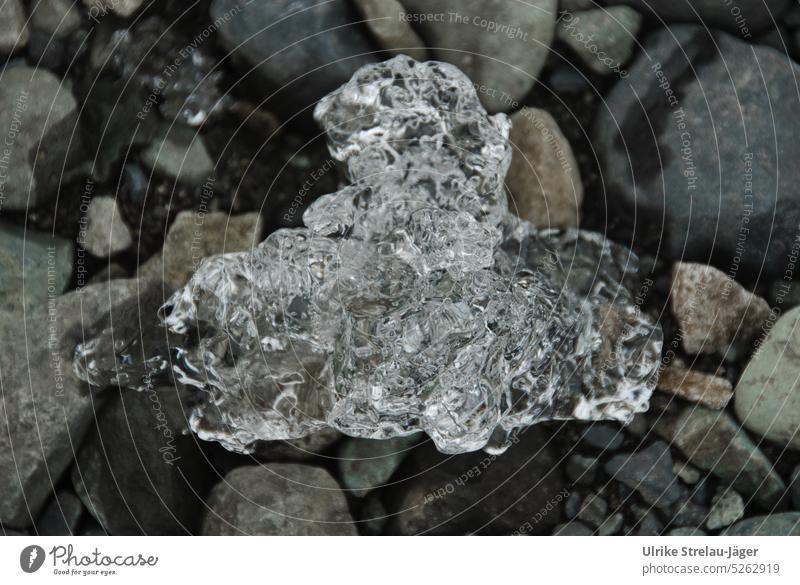 Eisbrocken zwischen Steinen kalt gefroren Frost Eiskristall frieren obenauf Kristallstrukturen eingebettet Gletschereis abgebrochen schmelzen kristallin