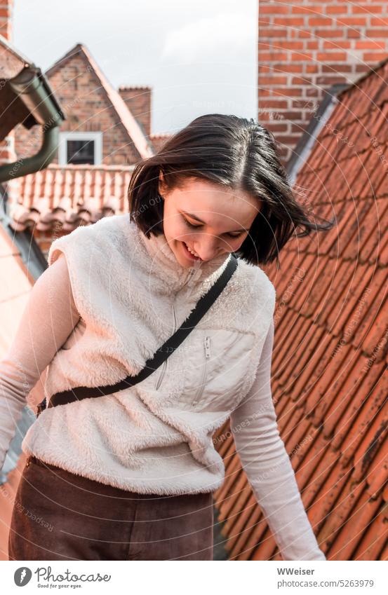 Eine junge Frau läuft über die Dächer der alten Stadt Mädchen lächeln glücklich abenteuerlustig mutig balancieren Ziegel Spitzdach Hansastadt Kleinstadt