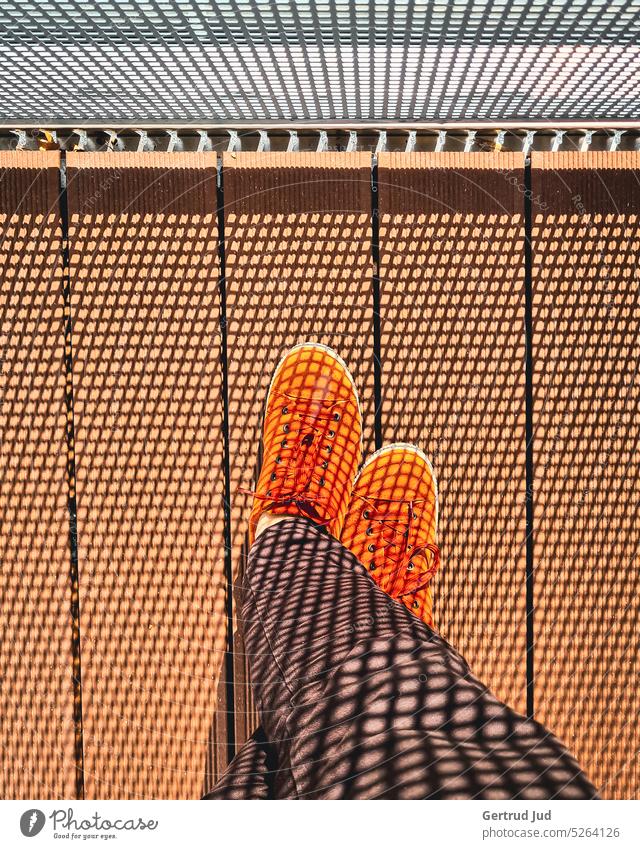 Orange Schuhe auf Balkon mit Schattenmuster Licht Lichtspiel Lichteinfall Schattenspiel Schattenwurf Muster Musterung Balkongeländer Sonnenlicht Sonnenschein