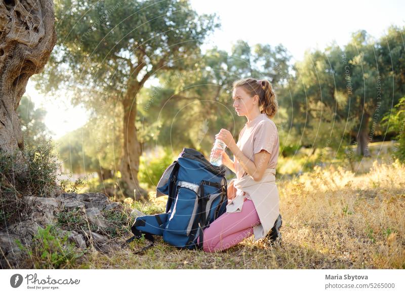 Junge Frau packt ihren Rucksack beim Wandern in der sommerlichen Natur. Konzepte von Abenteuer, extremes Überleben, Orientierungslauf. Ausrüstungen für die Wanderung.