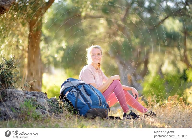 Junge Frau beim Wandern auf dem Lande. Mädchen ruht sich unter einem Olivenbaum aus. Konzepte von Abenteuer, extremes Überleben, Orientierungslauf. Backpacking-Wanderung