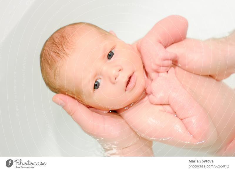 Ein junger Vater badet sein neugeborenes Baby. Elternschaft. erste Bad Pflege Papa Familie Hygiene Säugling Liebe Hand Papi Mann Badewanne schön Schönheit