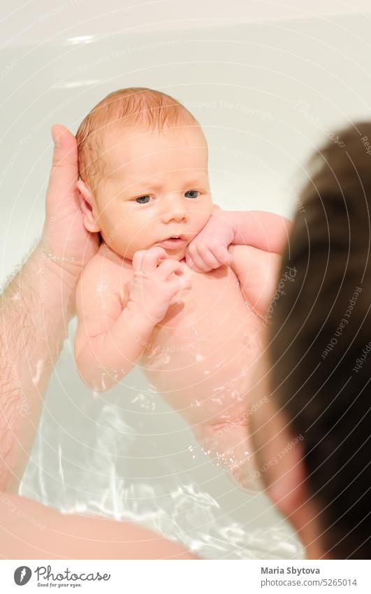 Ein Vater mittleren Alters badet sein neugeborenes Baby. Elternschaft. erste Bad Pflege Papa Lebensmitte Familie Hygiene Säugling Liebe Hand Papi Mann Badewanne