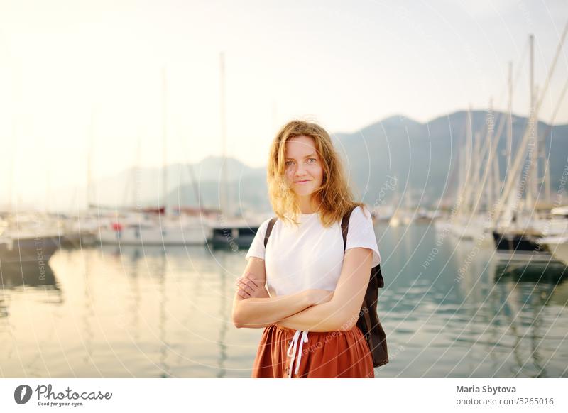 Charmante junge Touristinnen reisen an der Mittelmeerküste. Attraktives rothaariges Mädchen auf dem Hintergrund von Meer und Yachten. Yacht-Vermietung. Tourismus und Reisen