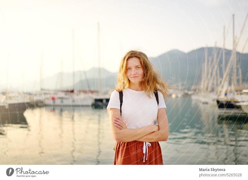 Charmante junge Touristinnen reisen an der Mittelmeerküste. Attraktives rothaariges Mädchen auf dem Hintergrund von Meer und Yachten. Yacht-Vermietung. Tourismus und Reisen
