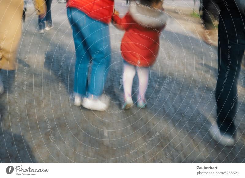 Fußgänger, deren Beine sichtbar sind, rote Jacken, Kopfsteinpflaster, Gehweg bei Spaziergang im Frühling Schuhe spazieren flanieren Eltern Kind sonnig