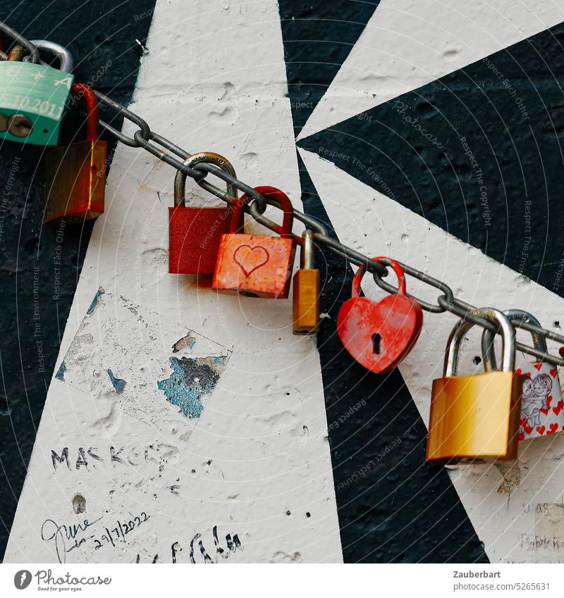 Schlösser in rot an Kette, aufgereiht vor schwarz-weißem Muster auf Segment der Berliner Mauer Schloss Liebe Liebesschwur Reihe Gruppe Hintergrund Romantik