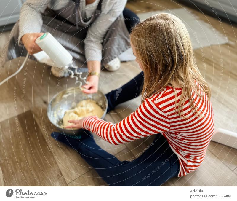 Frau und Kind kneten Teig mit Rührgerät auf dem Küchenboden Backen Brot Kuchen Mutter Mama Teigwaren Mehl Zutaten Schürze Fussboden Kindheit Essen zubereiten