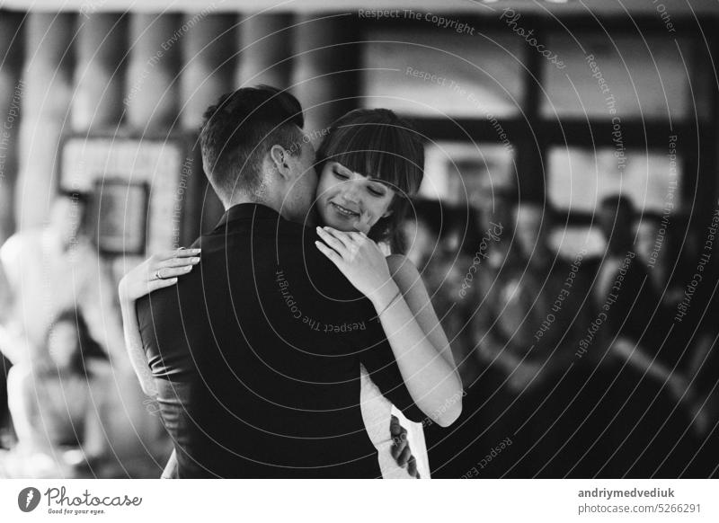 Junges hübsches Brautpaar tanzt in einem Restaurant und feiert eine Hochzeit. Schwarz-Weiß-Foto, eine Frau im Hochzeitskleid, ein Mann im Anzug. schön Liebe