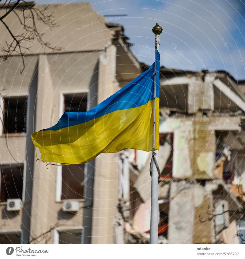 Flagge der Ukraine vor dem Hintergrund eines zerstörten Gebäudes in der Ukraine Ukrainer ununterbrochen urban Sieg Krieg abgenutzt gelb Konzept Patriotismus
